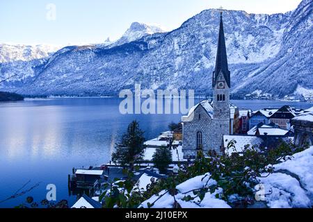 Vue sur un petit village avec église pendant l'hiver au milieu des montagnes à côté d'un lac Banque D'Images