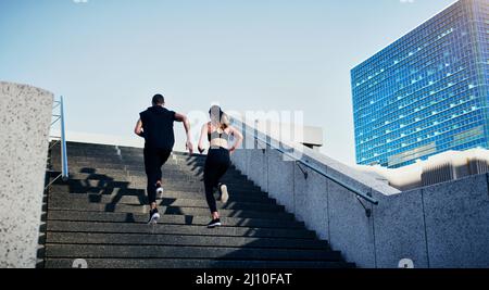 Faites ce qui fait circuler votre sang. Vue arrière d'un jeune homme et d'une jeune femme qui se rassemblent dans les escaliers de la ville. Banque D'Images