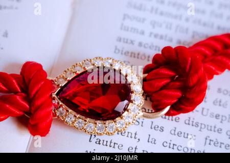 Un bracelet rouge contenant une grande pierre rouge au-dessus d'un livre ouvert Banque D'Images