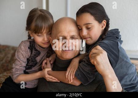 Grand-père ukrainien et deux petites-filles embrassant Banque D'Images