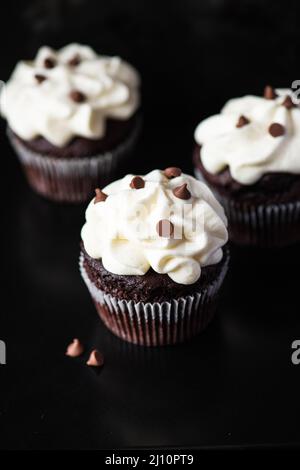 Cupcakes au chocolat riches avec glaçage à la crème fouettée et copeaux de chocolat sur fond de disque, Banque D'Images