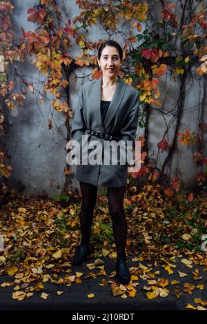bonne femme debout près du mur en automne Banque D'Images