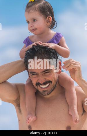 Père latin portant sa petite fille sur ses épaules souriant Banque D'Images