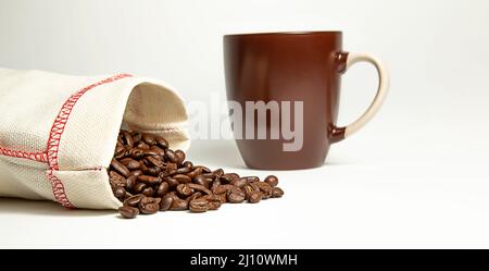 Des grains de café ont été déversés du sac sur un fond blanc. Banque D'Images