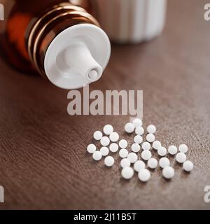 Bulles déversées sur une table en bois devant une bouteille de verre horizontale ouverte - bouchon debout à droite. Concept Homœopthy. Mise au point sélective. Banque D'Images