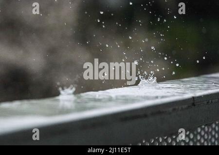 Les gouttes de pluie tombent et font des formes intéressantes sur un rail en acier froid Banque D'Images