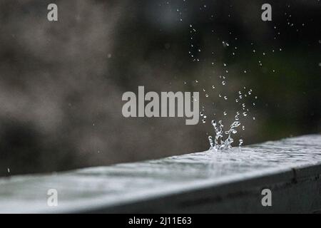 Les gouttes de pluie tombent et font des formes intéressantes sur un rail en acier froid Banque D'Images