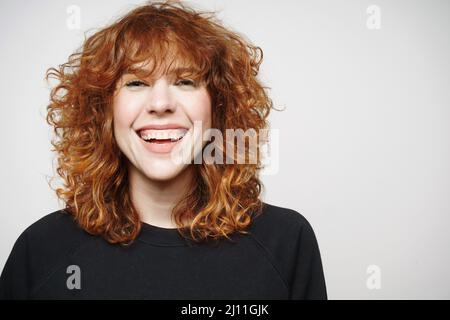 portrait d'une femme aux cheveux rougeâtres regardant l'appareil photo avec grand sourire et espace de copie Banque D'Images