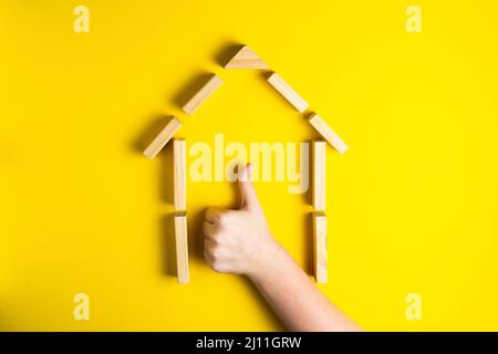 Vue de dessus de la main de l'enfant gros plan des blocs de construction montrant ok, maison, cabane en bois Banque D'Images