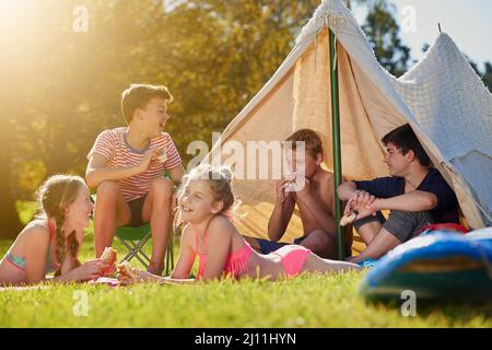 L'été appartient aux jeunes. Photo d'un groupe de jeunes amis qui traînaient à leur campement. Banque D'Images