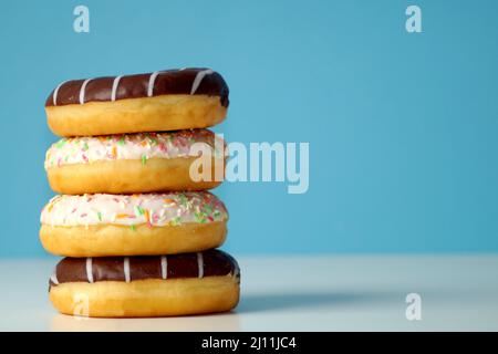 Délicieux beignets frais, multicolores et au chocolat, l'un à côté de l'autre, l'un sur l'autre Banque D'Images