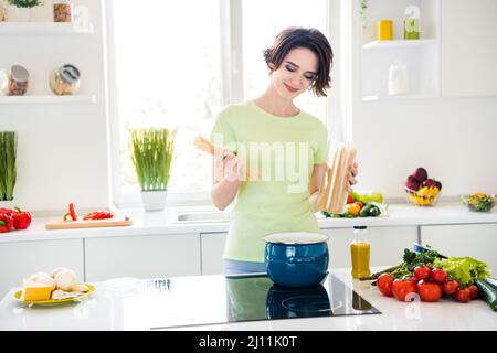 Photo de la personne assez positive préparant des spaghetti bouillante jour lumière cuisine maison à l'intérieur Banque D'Images