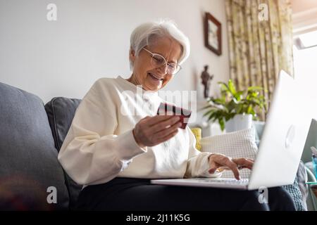 Femme senior faisant des achats en ligne sur ordinateur portable à la maison Banque D'Images