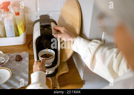 Gros plan d'une femme âgée préparant un café à la maison à l'aide d'une machine à espresso Banque D'Images