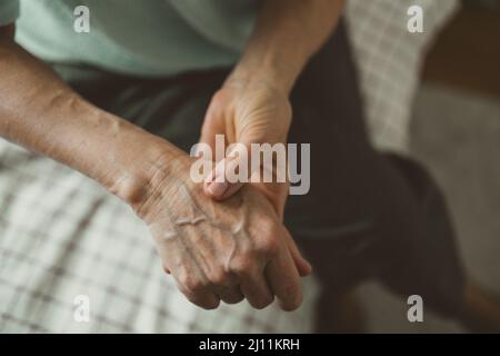 Femme senior avec arthrite frottant les mains Banque D'Images