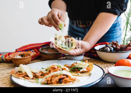 Femme mexicaine mains préparant tacos al pasteur avec sauce. Cuisine traditionnelle au Mexique Amérique latine Banque D'Images