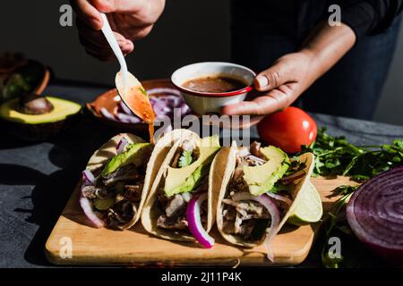 Une femme mexicaine prépare des tacos avec de la sauce cuisine traditionnelle au Mexique en Amérique latine Banque D'Images