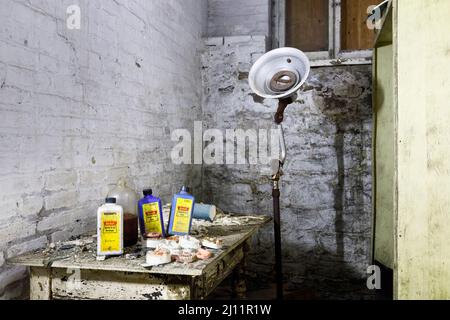 Moulages dentaires, produits chimiques à rayons X, prothèses dentaires et une vieille lampe dentaire à l'intérieur du sous-sol d'un asile abandonné. Banque D'Images