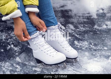 Gros plan sur une femme afro-américaine qui noue des lacets sur des patins à glace Banque D'Images