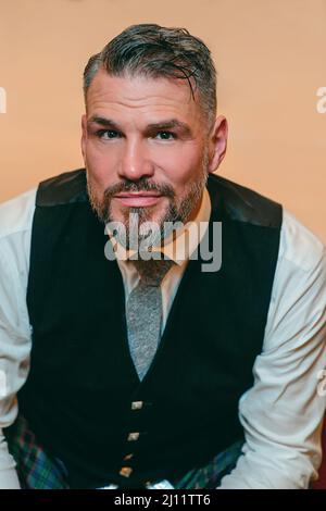 beau mûr courageux et élégant homme scotsman dans un four dans une chambre d'hôtel chic. Style, mode, style de vie, culture, voyage, concept ethnique. Banque D'Images