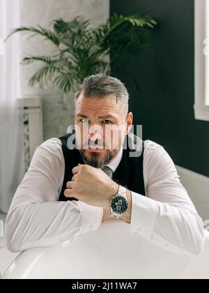 beau mûr courageux et élégant homme d'affaires écossais dans le kilt et le costume dans la salle de bains. Style, travail à la maison, mode, style de vie, culture, ethnique Banque D'Images