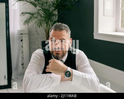 beau mûr courageux et élégant homme d'affaires écossais dans le kilt et le costume dans la salle de bains. Style, travail à la maison, mode, style de vie, culture, ethnique Banque D'Images