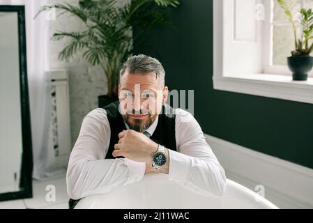 beau mûr courageux et élégant homme d'affaires écossais dans le kilt et le costume dans la salle de bains. Style, travail à la maison, mode, style de vie, culture, ethnique Banque D'Images