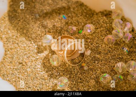 Deux anneaux de mariage sur le sable dans une coquille. Personne, attention sélective. Banque D'Images