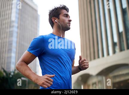 Courir le long de son itinéraire préféré de la ville. Photo d'un jeune homme qui fait du jogging dans la ville. Banque D'Images