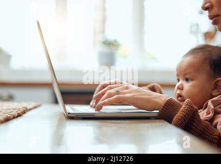 Jongler avec les responsabilités comme un patron. Photo courte d'une jeune femme méconnue travaillant à la maison avec son nouveau-né assis sur son ordinateur portable. Banque D'Images