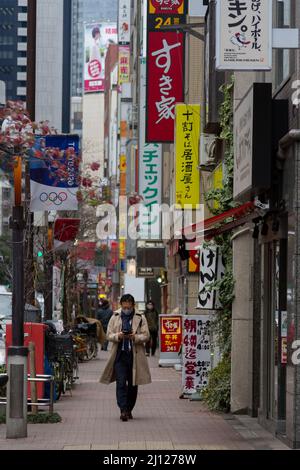 Un salaryman japonais, portant un masque facial contre COVID19 et utilisant un smartphone, dans une rue à Shimbashi, Tokyo, Japon. Banque D'Images