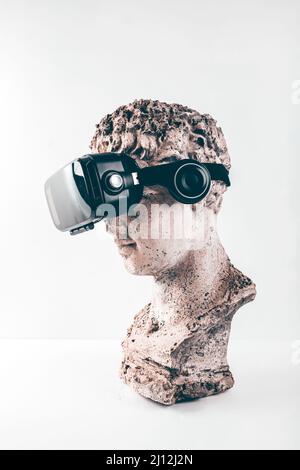 Statue ancienne avec lunettes VR sur fond blanc. Concept d'art et réalité virtuelle. Banque D'Images