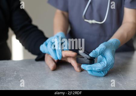 Gros plan sur la mesure de la saturation en oxygène des mains matures par oxymètre de pouls. Doigt personne âgée avec dispositif médical montrant un niveau de patient Banque D'Images