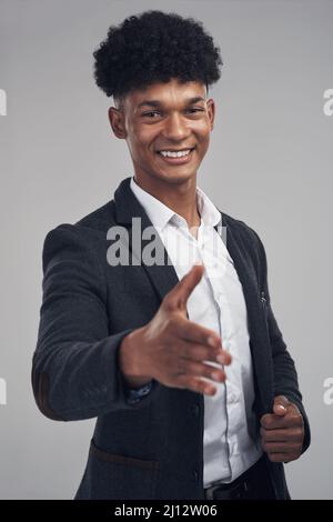 Ravi de faire votre connaissance. Studio photo d'un jeune homme d'affaires qui prolonge son bras pour une poignée de main sur fond gris. Banque D'Images