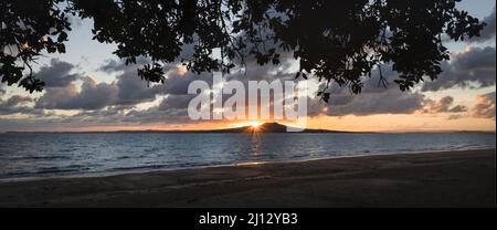 Soleil levant sur l'île Rangitoto, Milford Beach, Auckland. Banque D'Images