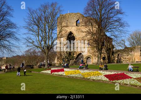 Personnes assises reposant en profitant du soleil (fleurs de la frontière lumineuse, ruines de la tour antique, ciel bleu) - Château de Knaresborough, North Yorkshire, Angleterre, Royaume-Uni. Banque D'Images