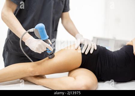 Le médecin applique un traitement par onde de choc sur le genou des femmes Banque D'Images