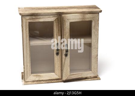 Gros plan d'une petite armoire en bois décorative avec portes en verre encadrées et poignées en métal sur fond blanc Banque D'Images