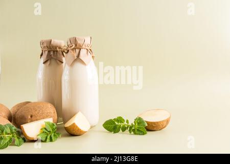 lait de légumes vegan à base de tubercules de pommes de terre en deux bouteilles de verre sur fond pastel avec une copie de l'espace Banque D'Images