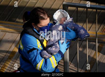 NOTE DES ÉDITEURS: Le visage de l'enfant a été pixélisé car le PA Picture Desk n'a pas pu obtenir la permission nécessaire pour photographier un enfant de moins de 16 ans sur des questions concernant leur bien-être. Un officier de garde-côtes porte un jeune bébé alors qu'un groupe de personnes considérées comme des migrants est amené à Douvres, dans le Kent, à partir d'un navire de la Force frontalière à la suite d'un incident de petit bateau dans la Manche. Date de la photo: Mardi 22 mars 2022. Banque D'Images