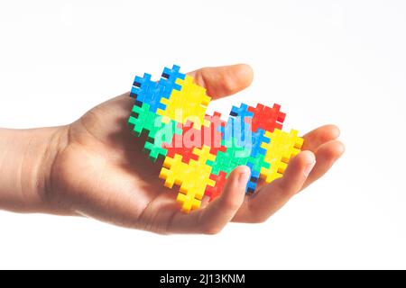 Les enfants tiennent le coeur de puzzle coloré sur fond blanc. Concept de journée mondiale de sensibilisation à l'autisme Banque D'Images