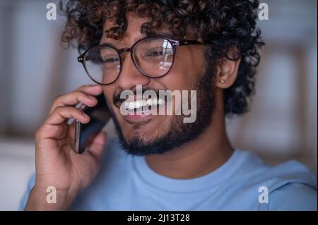 Un adorable homme en particulier rit pendant la conversation téléphonique Banque D'Images