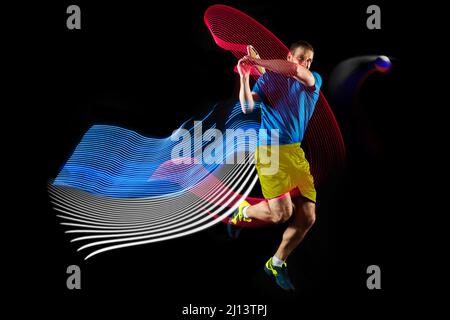 Portrait d'un jeune homme jouant au tennis isolé sur fond sombre avec des stipes de couleurs mélangées. Concept de sport, passe-temps, défis, paix, politique Banque D'Images