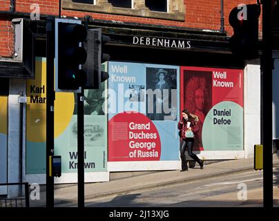 Jeune femme passant devant la succursale de Debenhams - maintenant hors des affaires - Harrogate, North Yorkshire, Angleterre Royaume-Uni Banque D'Images
