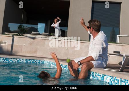 Une famille heureuse profite de vacances dans une maison de luxe avec piscine. Le couple senior passe du temps avec son fils pendant les vacances. Mise au point sélective Banque D'Images