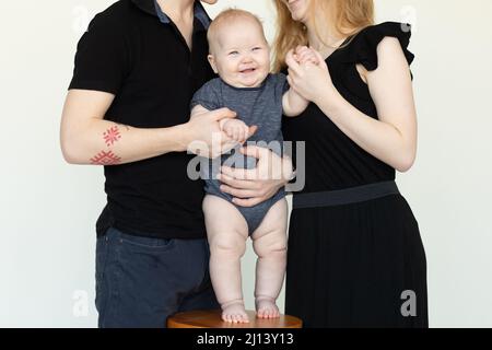 Rire bébé sur chaise. Photo rognée de la famille traditionnelle, debout et embrasser ensemble. Soins pour bébé, protéger Banque D'Images