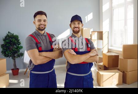 Deux jeunes employés joyeux qui travaillent dans des combinaisons sourient devant la caméra. Banque D'Images