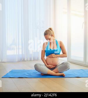 Maman vous aime, un peu. Photo d'une femme enceinte travaillant sur un tapis d'exercice à la maison. Banque D'Images