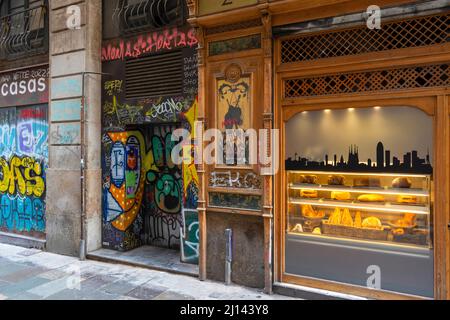 BARCELONE ESPAGNE QUARTIER GOTHIQUE BARRI GÒTIC ESPACE ARTISTIQUE UNE PORTE PEINTE COLORÉE ET UNE FENÊTRE DE PÂTISSERIE Banque D'Images