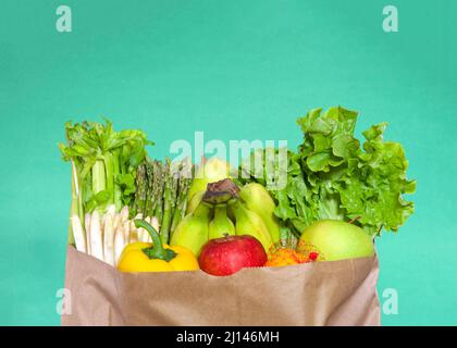 Dessus de sac d'épicerie en papier brun farci de fruits et légumes. Céleri, asperges blanches et vertes, bananes, laitue, poivron jaune, rouge A. Banque D'Images